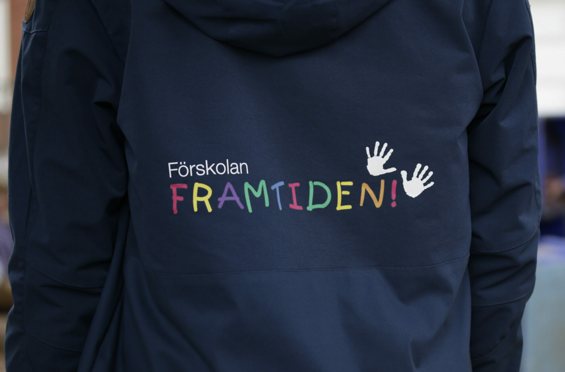 Bild på en förskolelärares rygg med Förskolan Framtidens logga.